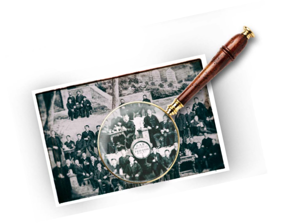 Une loupe permet de voir de plus près une partie d'une vieille photographie représentant un groupe de personnes en plein air.
