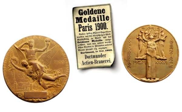 Trois objets sont exposés : deux médailles d'or et une coupure de journal. La coupure de journal fait état d'une récompense décernée à Paris en 1900.