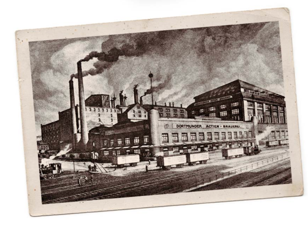 Une carte postale d'époque représente une grande brasserie industrielle dont les cheminées crachent de la fumée, sur fond de ciel nuageux.