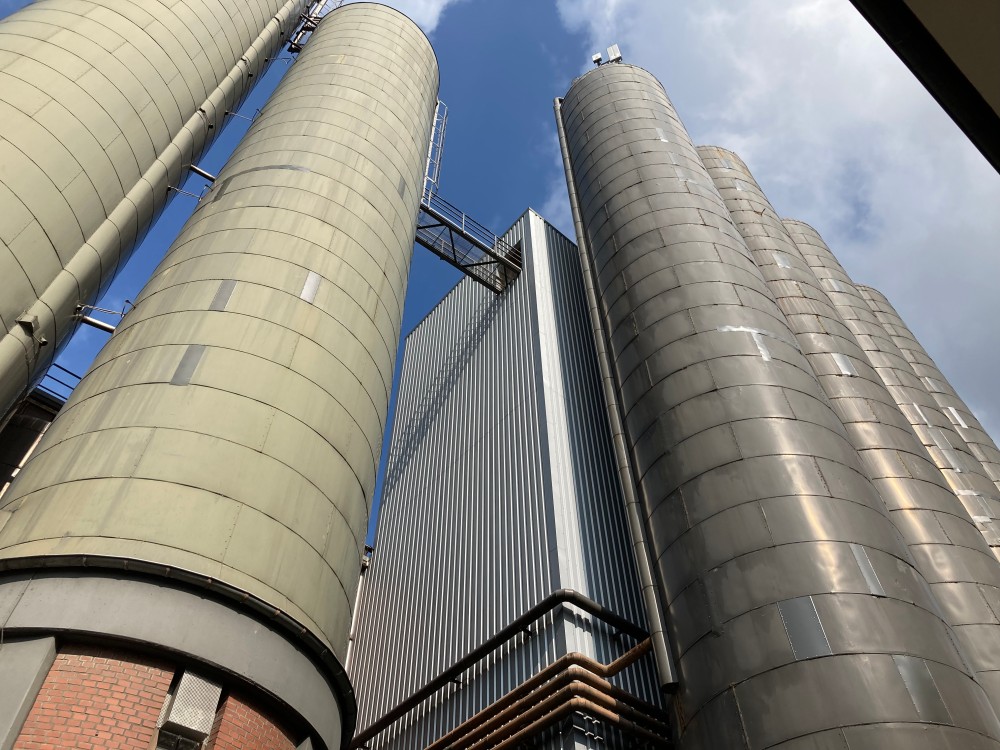 Trois grandes tours cylindriques reliées par des passerelles, vues en contre-plongée sous un ciel dégagé.